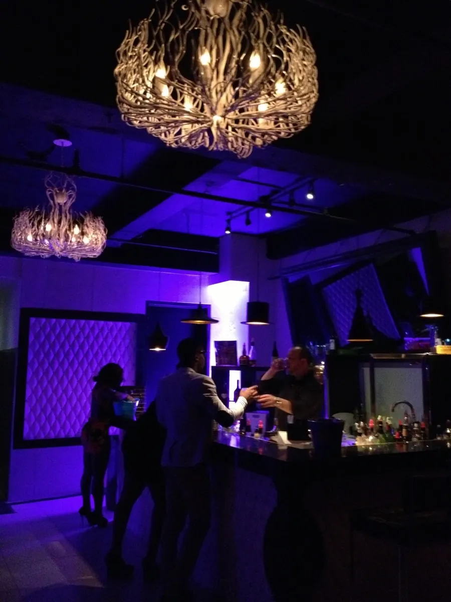 Bar counter under purple lighting and branch chandeliers at Espaces des Arts in Montreal