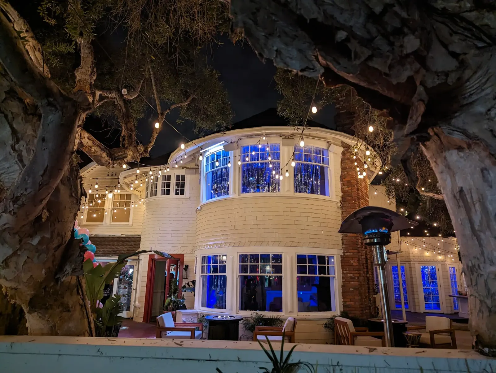 Night exterior of The Victorian tower building with festival lights and crowd in LA