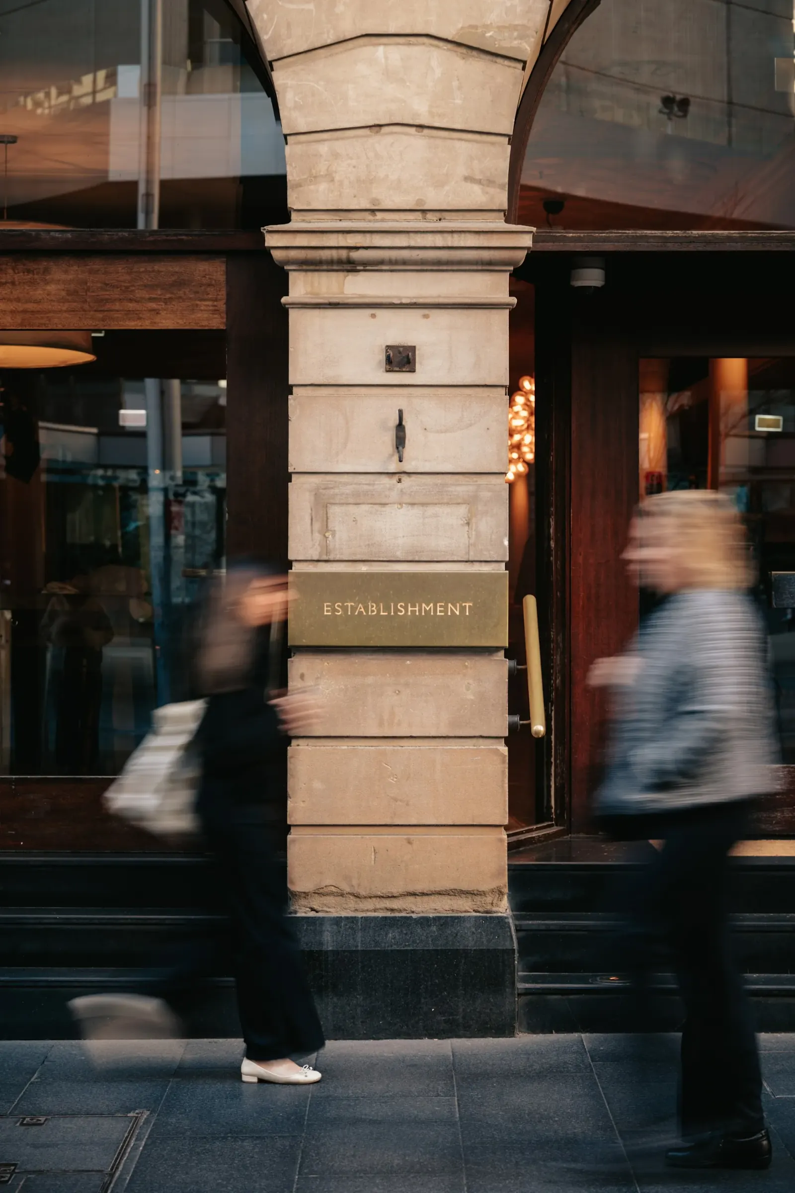Pedestrians pass the sandstone Establishment Bar entrance with signage on George Street Sydney