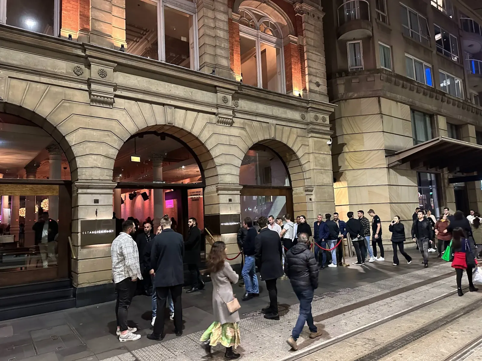 Evening crowd queues at the arched entrance of Establishment Bar Sydney for a Saturday night out