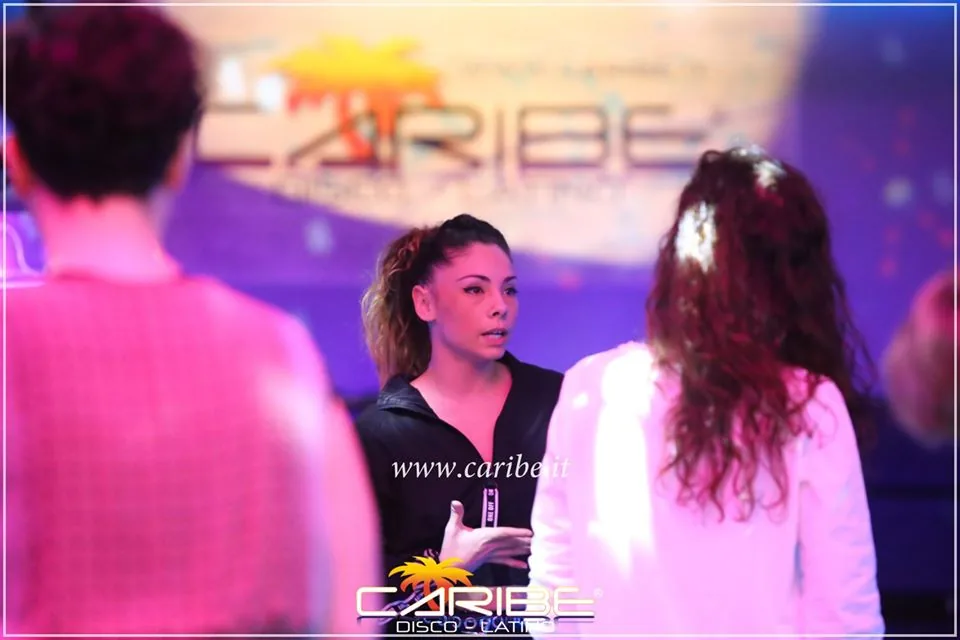 Dance instructor in conversation in front of Caribe branded backdrop at Discoteca Caribe Verona