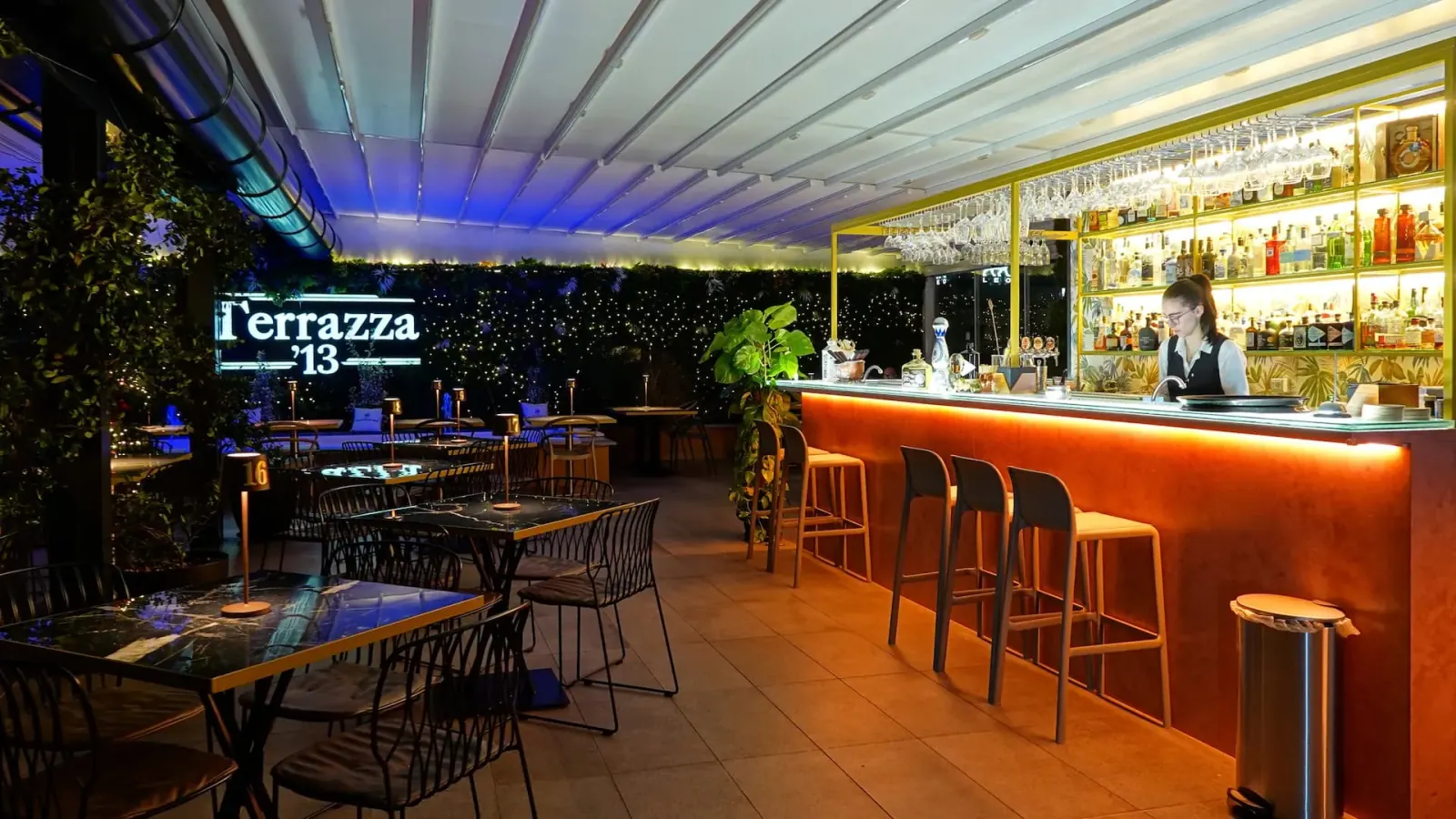 Illuminated bar with Terrazza 13 signage and lounge seating in Milan