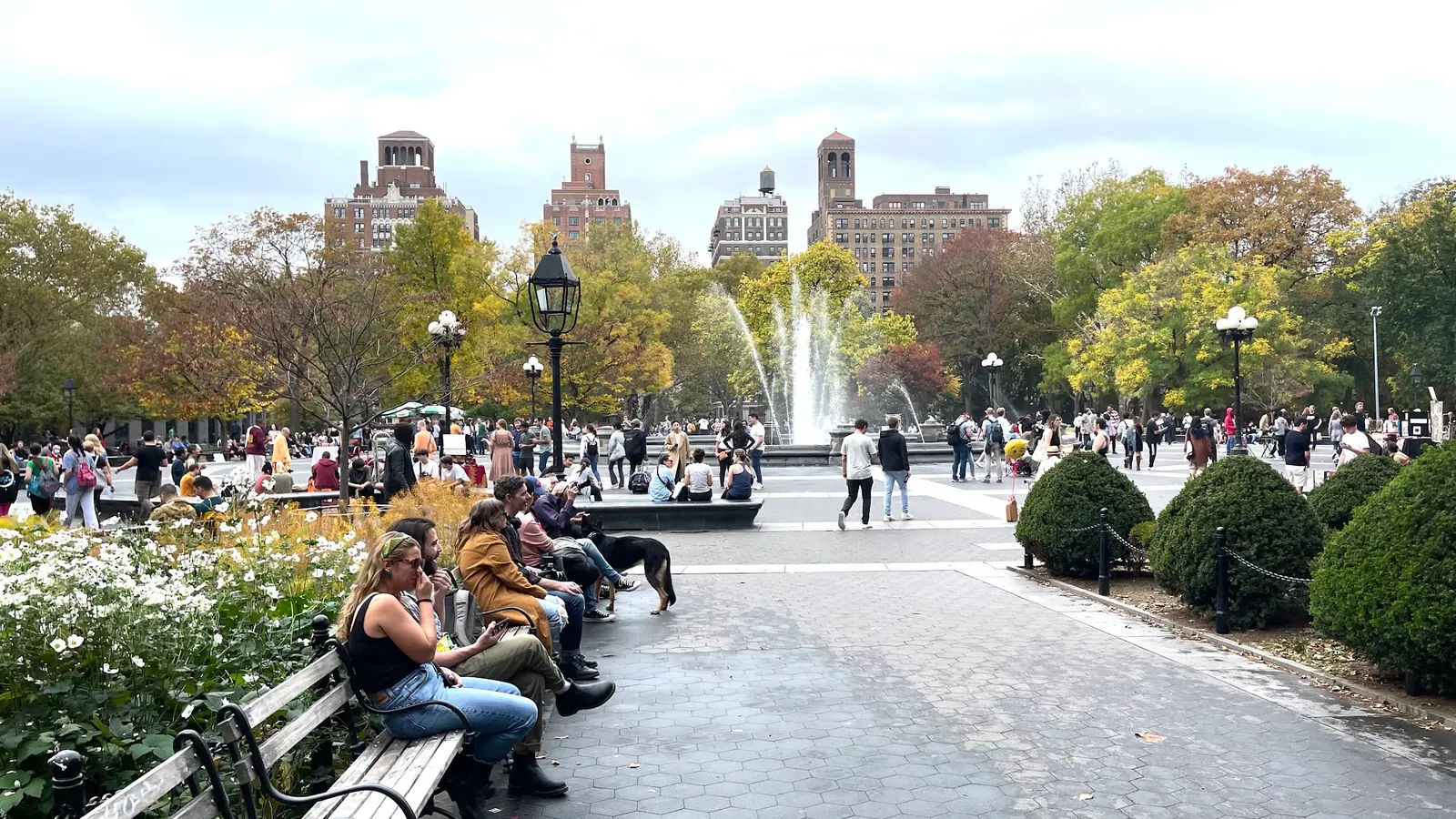 Crowd around the fountain plaza on an autumn day at Washington Square Park