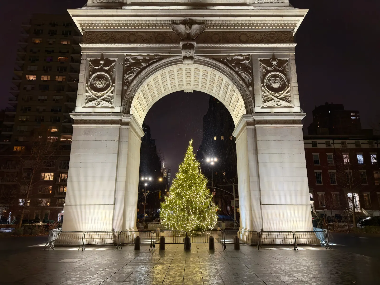 Washington Square Park arch lit at night with an illuminated tree beneath it