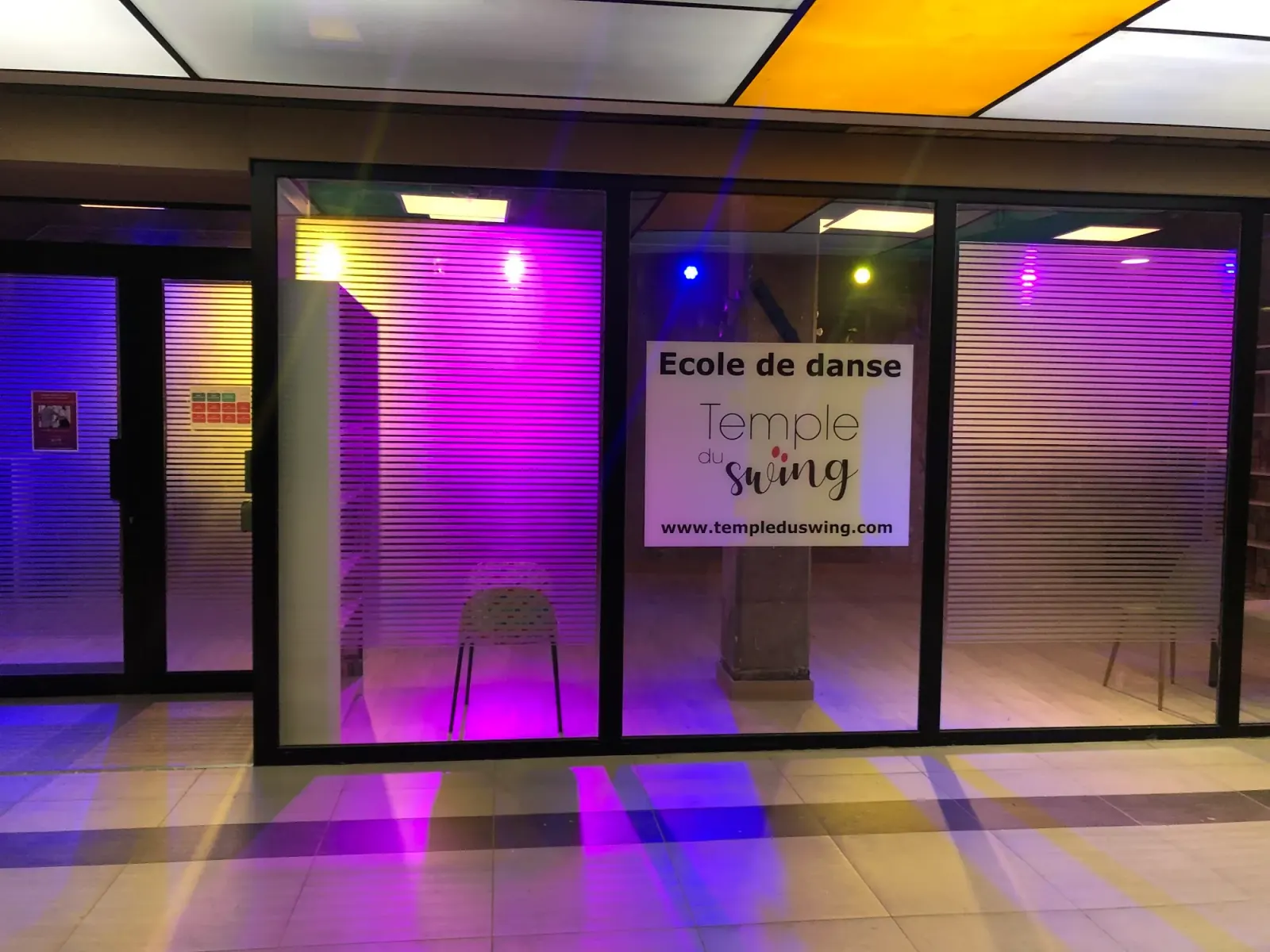 Temple du Swing storefront in Paris lit with purple and yellow ambient lighting at night