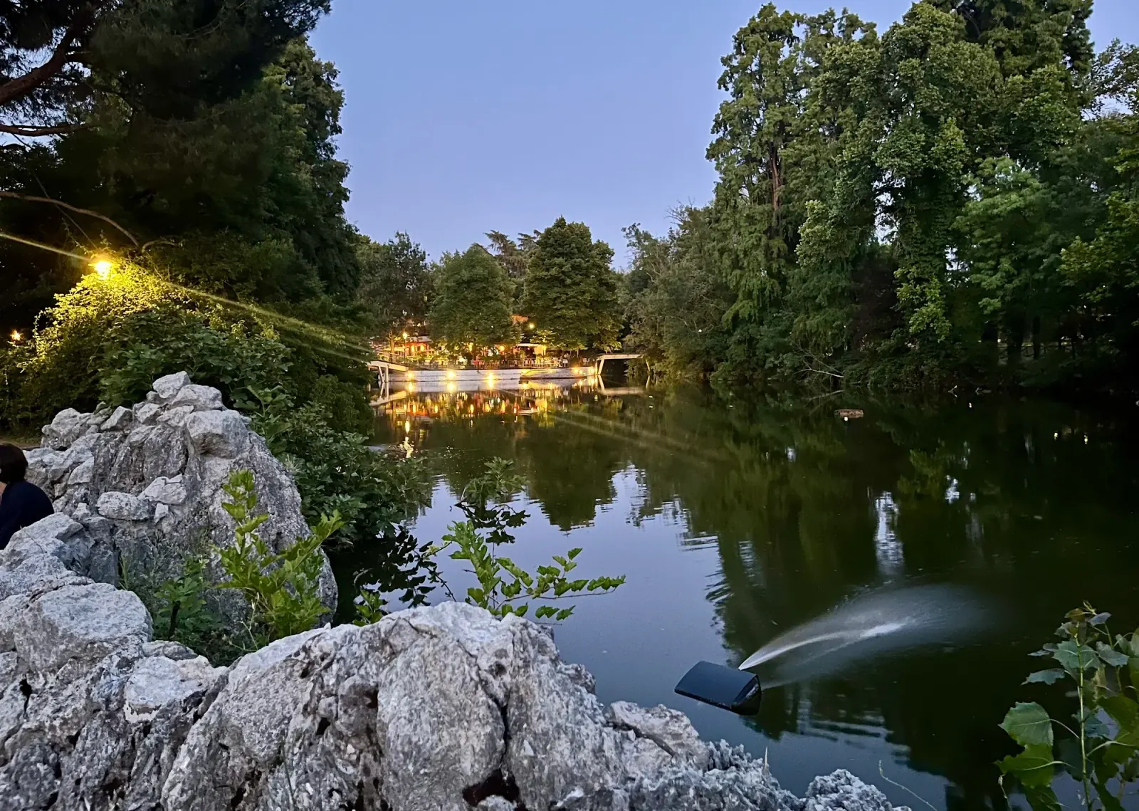 Park lake at dusk with Chalet dei Giardini Margherita lit venue Bologna