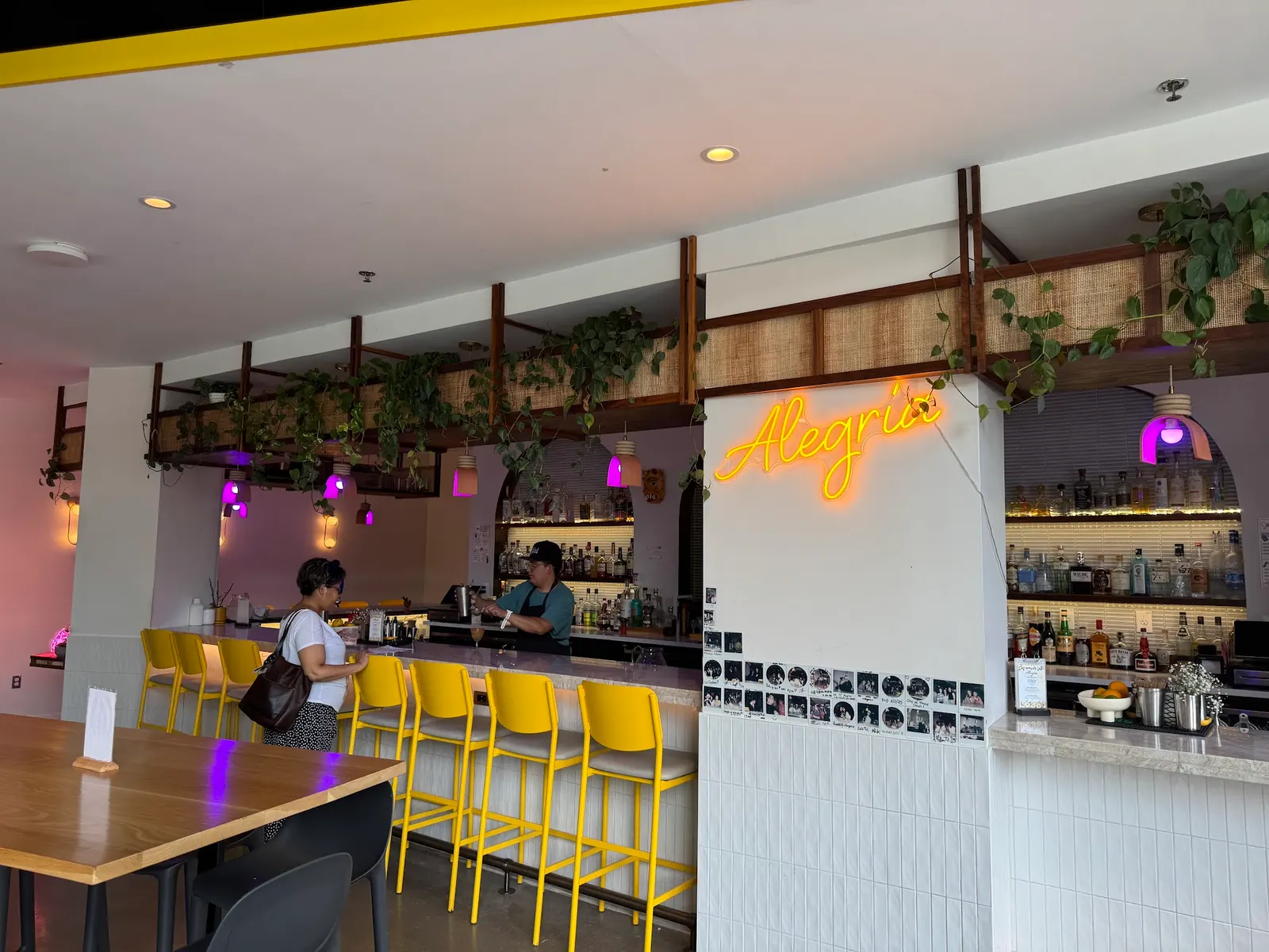 Bar with yellow stools and an Alegria neon sign inside Bryant Street Market in Washington