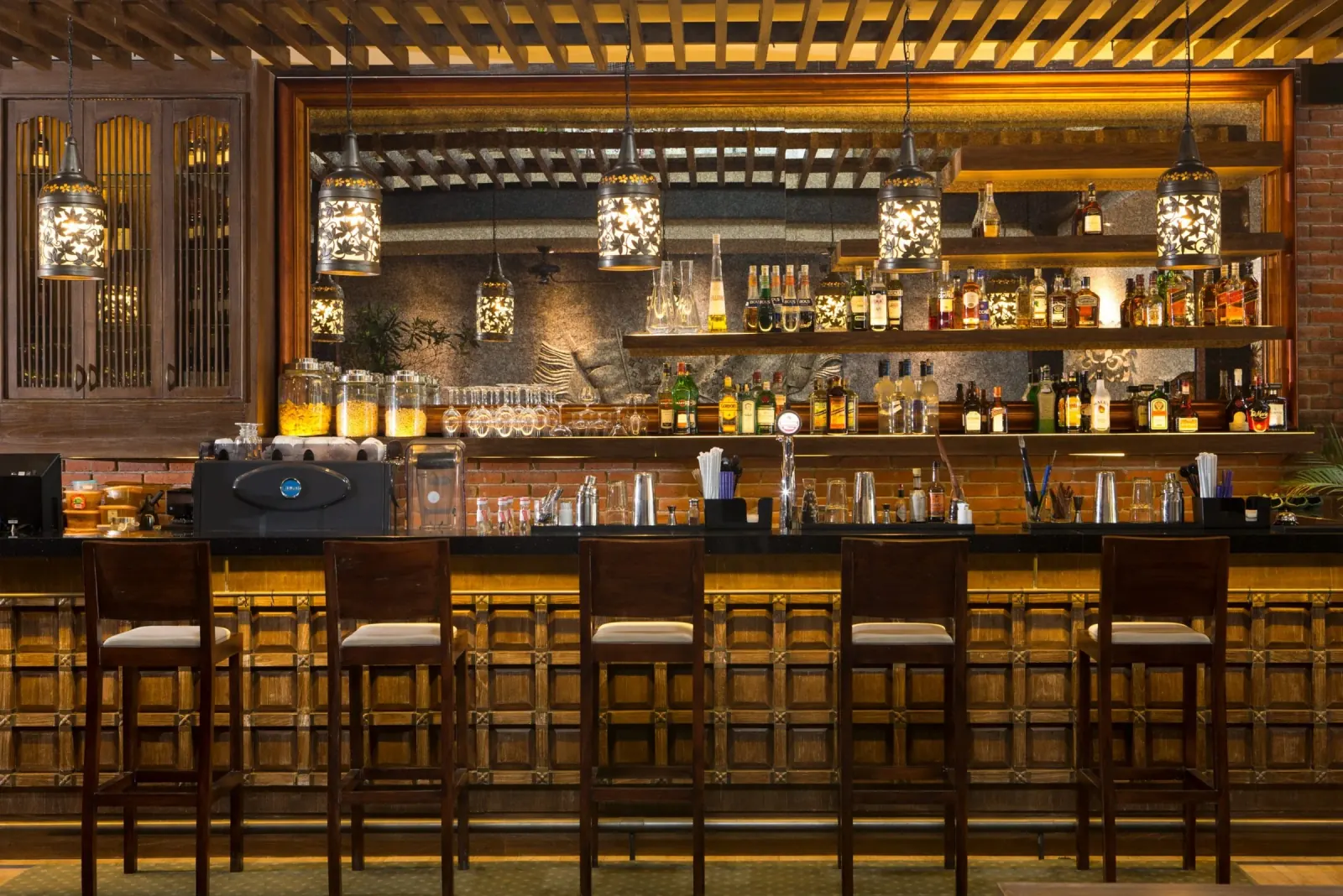 Warmly lit wooden bar with hanging lanterns at Enclave in Bali, Indonesia