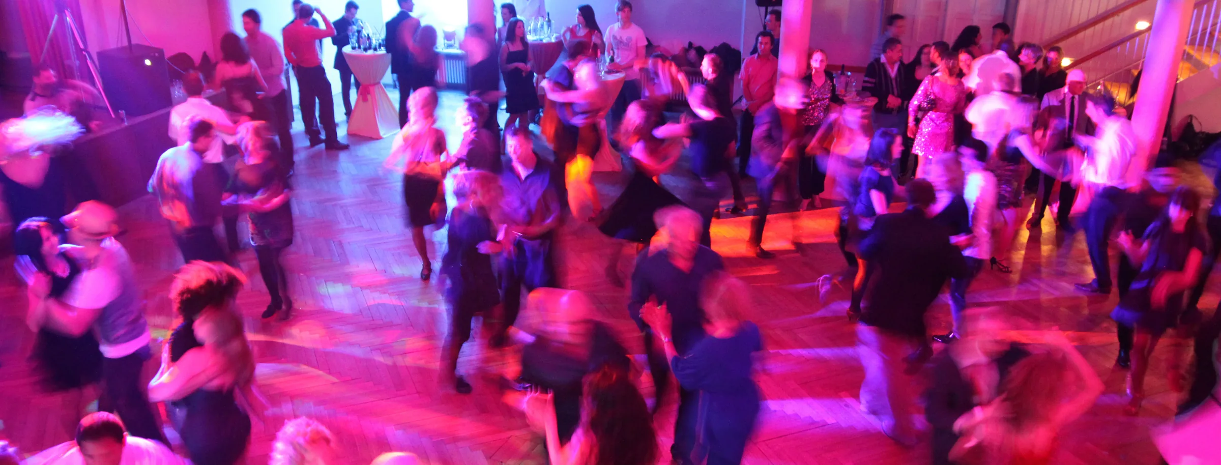 Packed Salsa social dance floor with motion-blur and pink lights at Salsamas in Munich