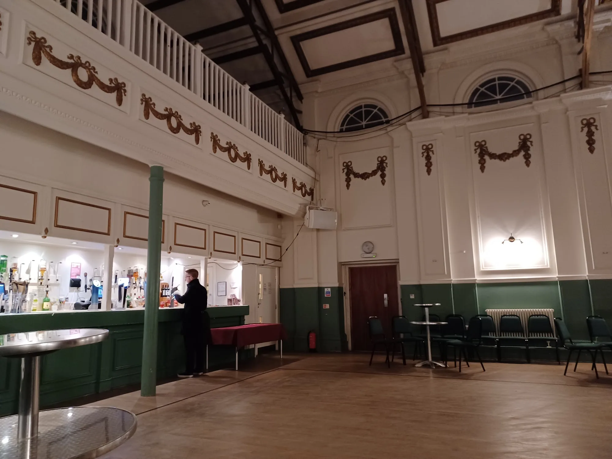 Ornate interior dance hall with wooden floor, balcony and bar at Hammersmith Salsa & Bachata Club in London
